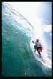 Фотография серфингиста покрытого водной пылью разбитой волны