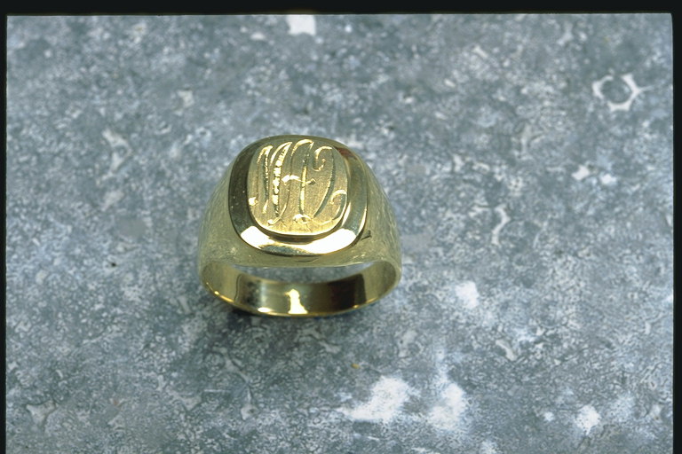 Печатка з світлого металу, золотистий матеріал з літерами в середині
