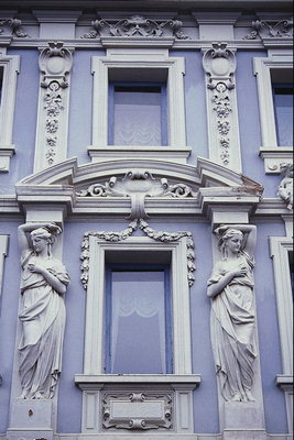 Фасад будівлі в бузкові тонах. Колони у вигляді дівчат, арки