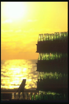 Ящики з порожніми пивними пляшками на тлі яскраво-жовтого сходу сонця
