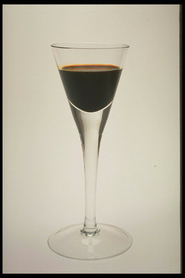 Egy sötét színű ital a pohárban egy hosszú szárral