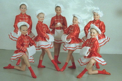 Дівчата в червоно-білих костюмах. У білих шапках і з муфтами