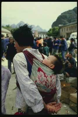 Дитина в гамаку на спині мами