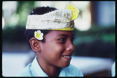 الصبي مع باقة من الورود البيضاء والصفراء وراء الأذن ورأس