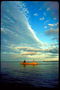 Фотографія різнобарвного неба і людей що пливуть по ранковому озера